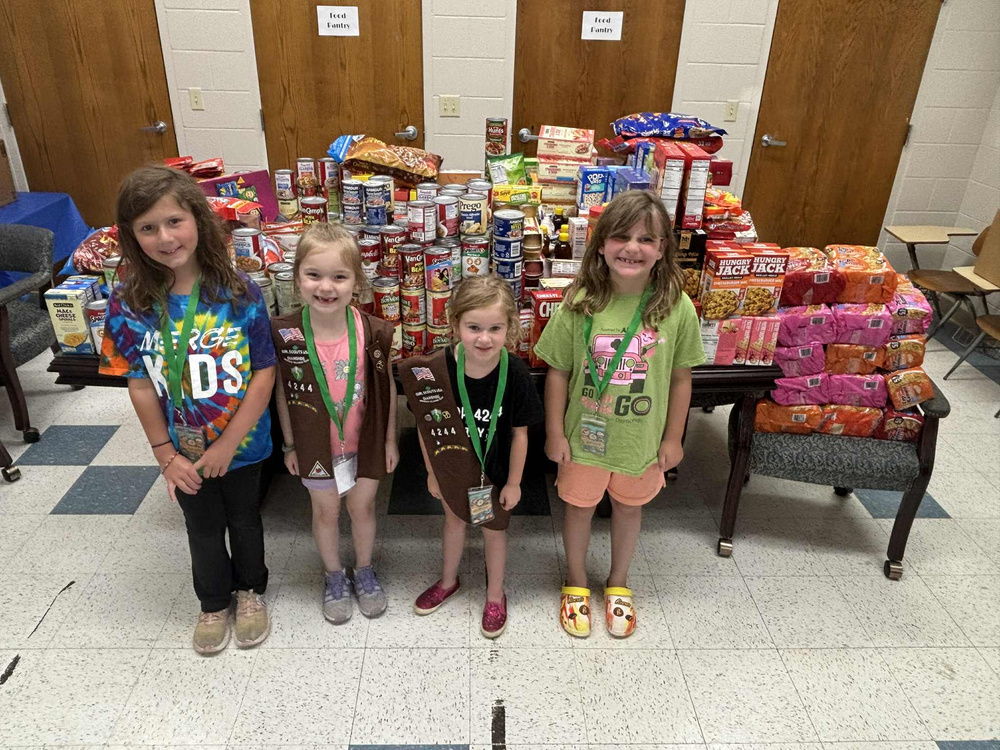 Members of Girl Scouts Troop 4244 standing in front of a table of donations..